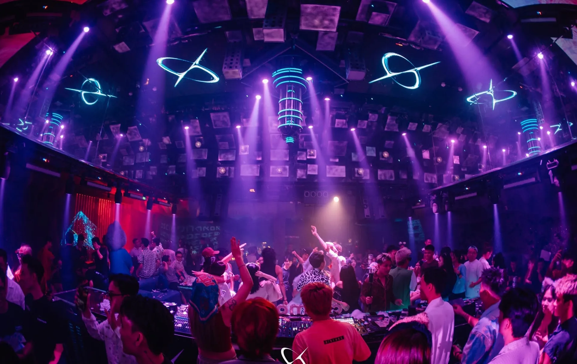 Trần vòm LED với biểu tượng quỹ đạo, tia đèn tím và bốt DJ giữa đám đông tại Cosmos Club Hà Nội